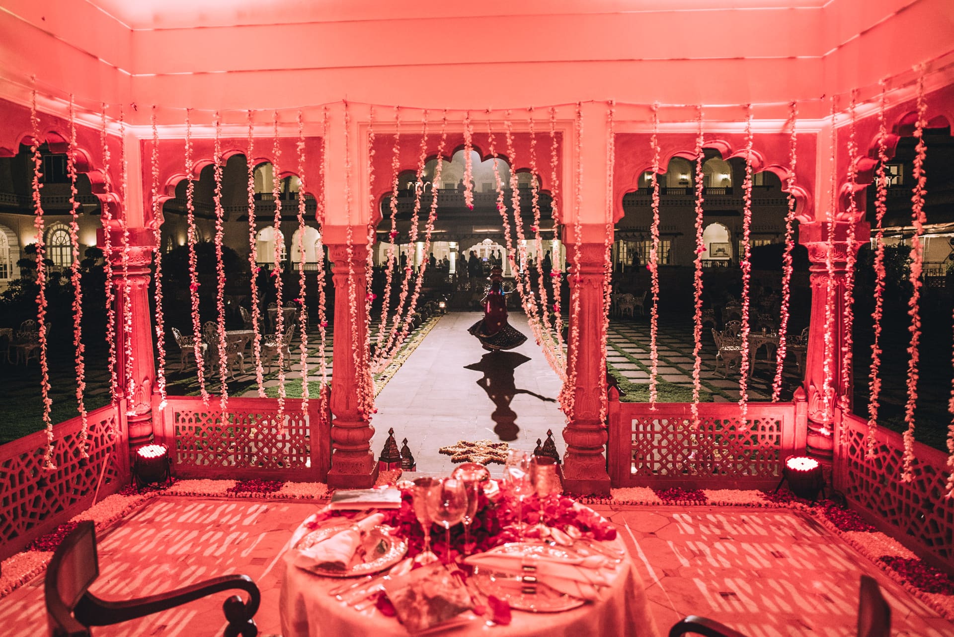 Pavilhao de palacio iluminado de vermelho, mesa posta.
