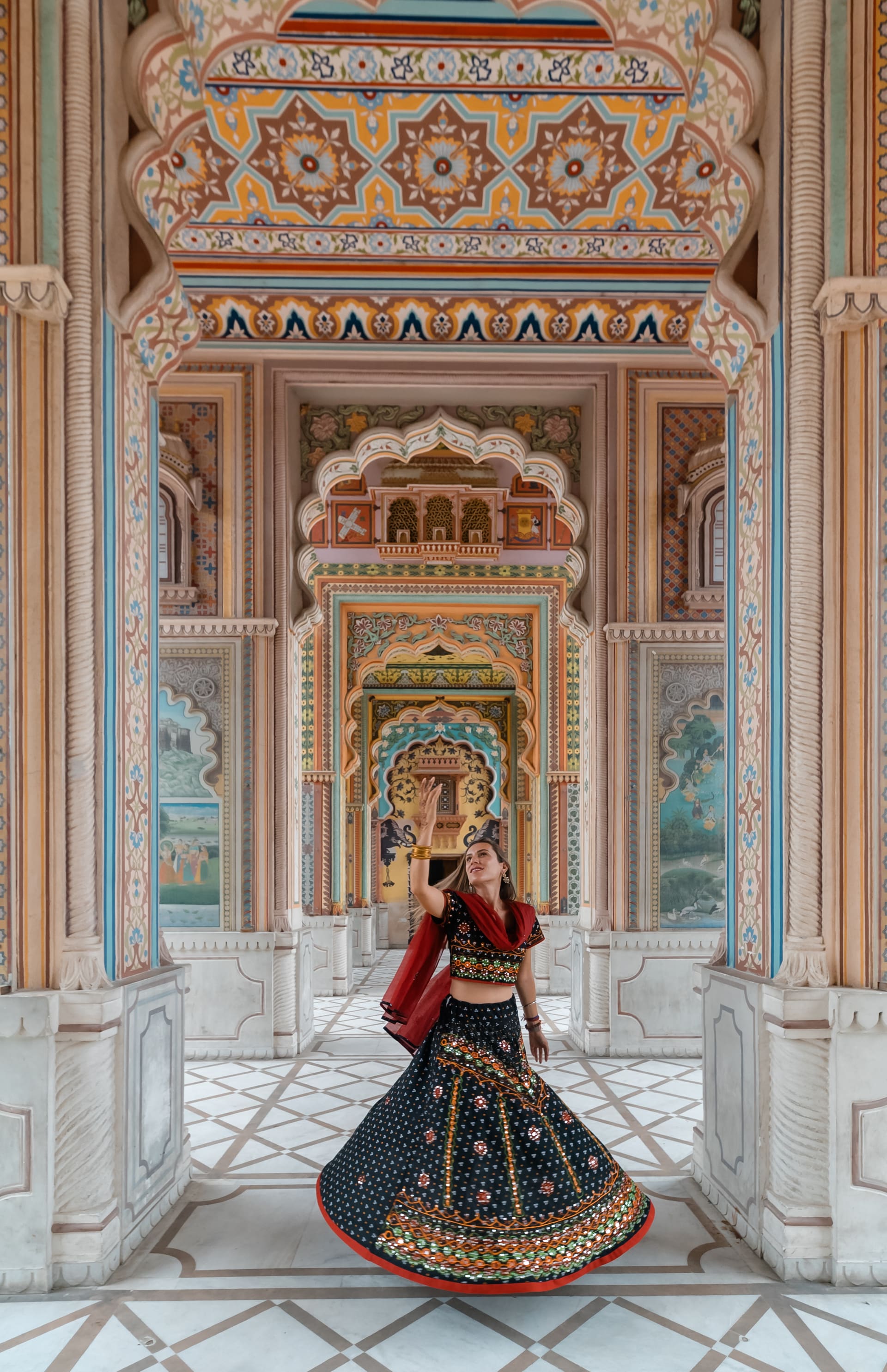 Pessoa em traje tradicional sob um portal ornamentado, vista para o lago.
