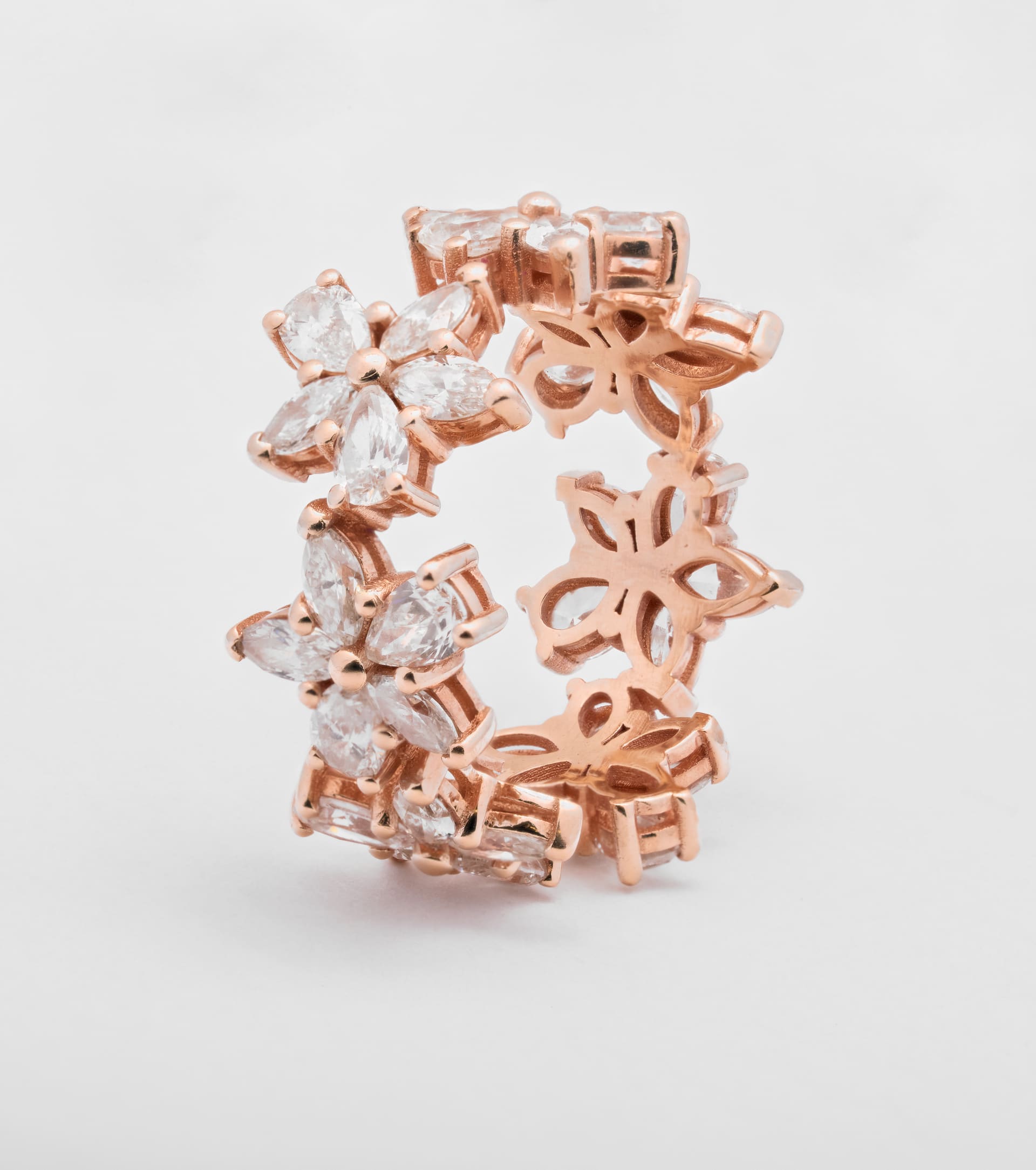 Peca de joalheria em ouro rose sobre fundo branco.
