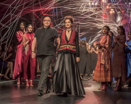 Estilista e modelo encerram o desfile de Tarun Tahiliani sob uma instalacao de fios.